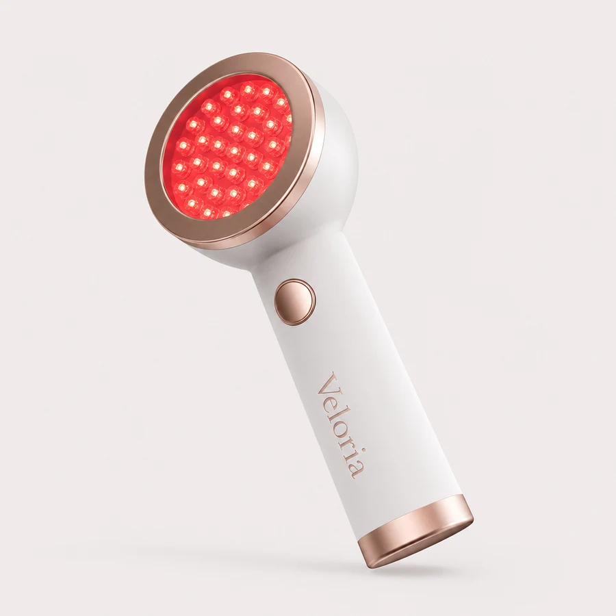 The Veloria Lumen Halo, a white handheld device with a round rose gold bezel and a dense red LED array